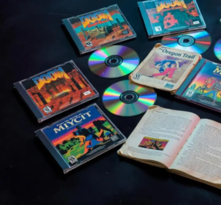 Disques PC rétro, manuels et pochettes illustrées disposés sur une table sombre