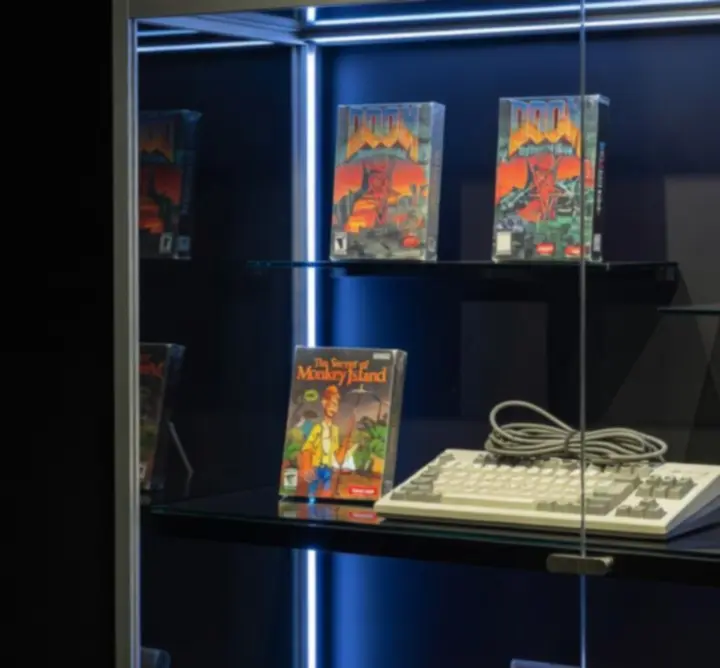 Vitrine premium rétro avec jeux PC de collection éclairés par des néons violets et bleus.